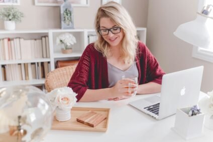 Woman sitting in front of her computer holding a cup - working from home