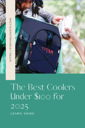 A child wearing green pants looks curiously at a navy-blue Titan cooler while an adult hands a juice pouch to them. The text overlay reads 'https://fortheloveto.com' on the left side and 'The Best Coolers Under $100 for 2025' at the bottom with 'Learn More' written below.