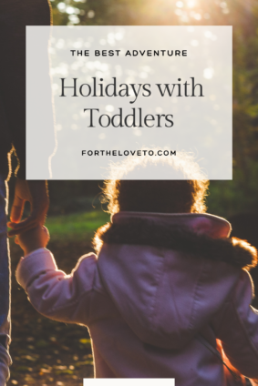 A toddler holding hands with an adult on a scenic outdoor adventure, representing the best adventure holidays with toddlers