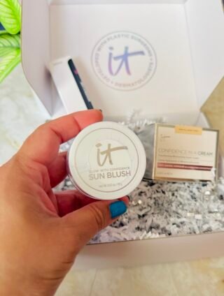 Glow With Confidence Sun Blush by IT Cosmetics held in hand, box in background.