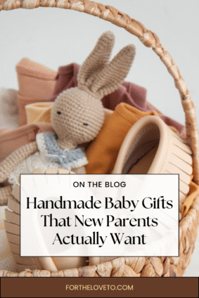 Woven basket filled with neutral-toned handmade baby gifts including a knitted bunny, leather baby moccasins, and folded baby clothes. Text overlay reads “Handmade Baby Gifts That New Parents Actually Want – fortheloveto.com.