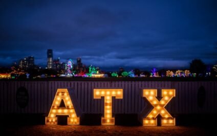 ATX marquee lights glowing at night with Austin skyline in the background during a family vacation in Austin TX.