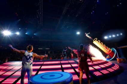 Circus performers launching from a cannon under bright lights at Ringling Bros. and Barnum & Bailey® The Greatest Show On Earth®, thrilling the crowd with stunts and music.