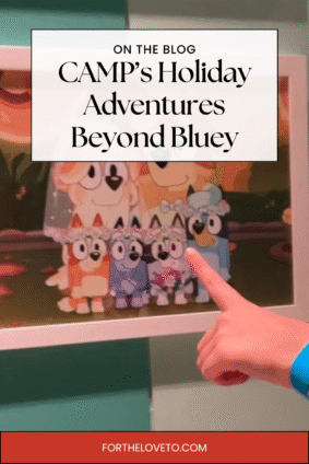 Child pointing at a framed Bluey family picture during the Bluey x CAMP holiday experience — showcasing interactive family fun at CAMP NYC.