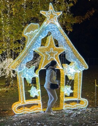 Guest walking through a star-shaped light tunnel at the LuminoCity Holiday Lights Festival surrounded by golden and white twinkling lights.