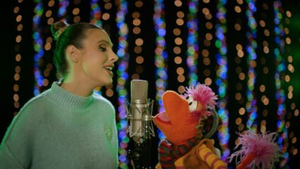 Lele Pons singing a holiday duet with Gobo from Fraggle Rock in a festive studio scene from The First Snow of Fraggle Rock special.