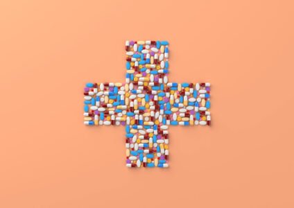 managing medications for seniors concept with pills arranged in cross shape on orange background