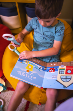 Child using the Glo Pals Magic Magnifier to reveal glowing hidden images while reading an interactive Light-Up Library storybook.