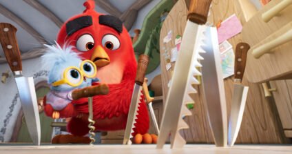 Red carefully carries his baby through a kitchen in The Angry Birds Movie 3, highlighting the movie's fun parenting adventure.