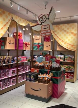 Amazon Top Toys pop-up inside FAO Schwarz, featuring fox plush, toy shelves, gift boxes, and an owl decoration.