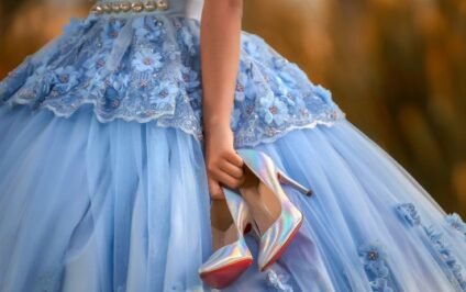 Quinceañera planning ideas featuring a girl wearing a blue ball gown and holding her dress shoes