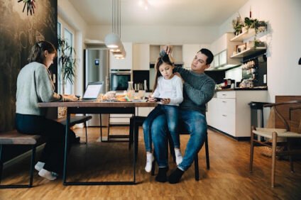 Parents and child gathered around a kitchen table, illustrating planning a family budget with irregular income.