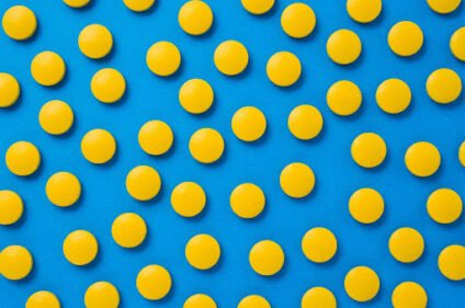 Yellow round tablets arranged on a bright blue background, illustrating dietary supplement safety.