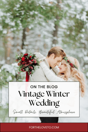 Couple embracing among snow-covered trees, with a red floral crown and burgundy bouquet showing how to add vintage charm to a winter wedding.